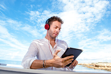 Man while using ipad beach bar by the sea enjoying music freedom sea on background
