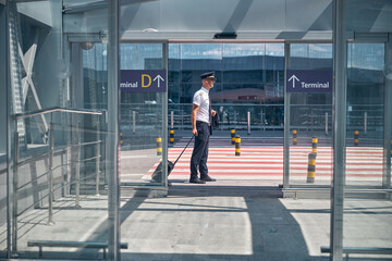 Fototapeta na wymiar Handsome male pilot standing outside airport terminal