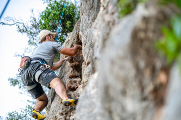 A man climbing a rock with a harness