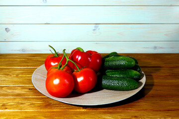 Ripe tomatoes, cucumbers and bell peppers on a wooden dish. Vegetarian food, healthy food, diet. Place for text.