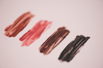 Swatches of colorful liquid lipstick over white closeup. Selective focus.