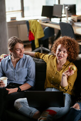 Girlfriends talking and laughing in office. Beautiful women drinking coffee in the office