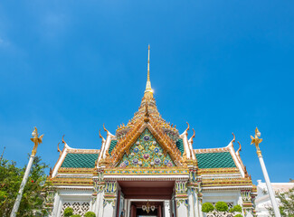 Fototapeta premium Art at facade and entrance door in The Temple of Emerald Buddha, the most beautiful landmark in Bangkok, Thailand, under summer blue sky