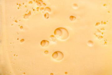 Cheese slices background. Close-up of square slices of radamer cheese. Pieces of Swiss cheese. Maasdam is a hard Dutch cheese with large holes.