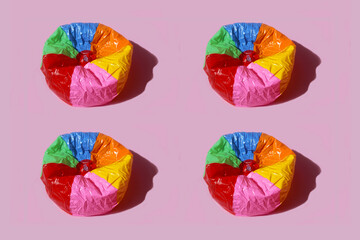Imagen de balon de playa desinflado con rayas de colores sobre fondo rosa pastel © minerva