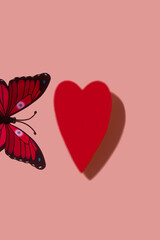 Fondo de san valentin con un corazon rojo y una mariposa volando a su alrededor