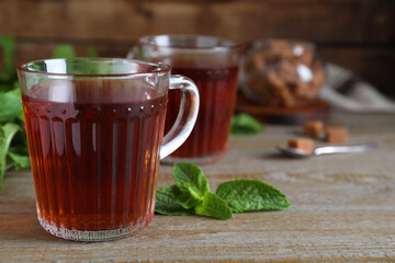 Cup with hot aromatic mint tea on wooden table, closeup. Space for text
