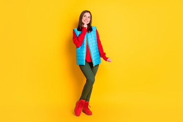 Full body size photo of pretty cute young lady dreamy look empty space hand chin smiling girlish posing wear green pants blue vest red sweater boots isolated bright yellow color background