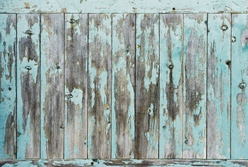 Old cyan blue wooden plank door with texture and part of the peeled paint.