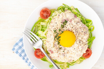 Carbonara sauce. Fried ham in heavy cream and with raw egg yolk and cherry tomatoes. Carbonara pasta made with fresh zucchini noodles.
