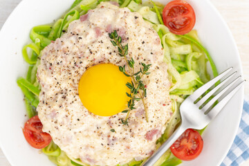 Carbonara sauce. Fried ham in heavy cream and with raw egg yolk and cherry tomatoes. Carbonara pasta made with fresh zucchini noodles.