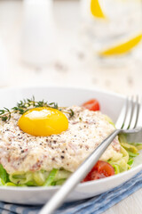 Carbonara sauce. Fried ham in heavy cream and with raw egg yolk and cherry tomatoes. Carbonara pasta made with fresh zucchini noodles.