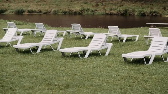 white loungers stand in rows on green grass empty