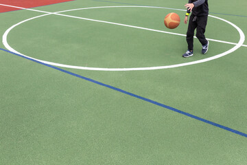 Artificial rubber-polymer coating of a modern multifunctional sports ground. A teenager plays a...