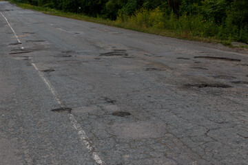 Very bad road in Russia. The asphalt road is all in holes in the middle of the forest.