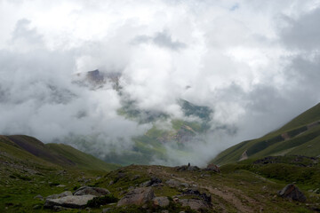 Mountain range in the clouds. Mountain pass in the fog. View of the mountain valley in the fog from the pass. Caucasus Mountains, Russia.