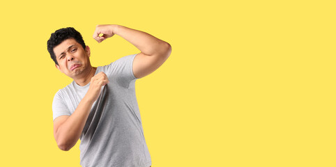 Asian Man sweating excessively smelling bad isolated on yellow background in studio With copy space.