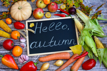 Autumn composition of vegetables and fruits with text Hello Autumn on rustic wooden background. Top view
