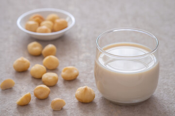 Macadamia milk in glass and macadamia nuts on table