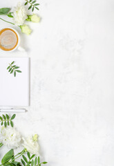 Cup of coffee, eustoma, pistachio greenery, notepad and pen on concrete background