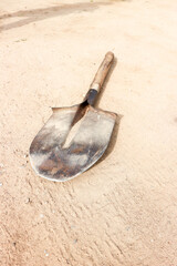 Old rusty shovel with wooden handle in the sand