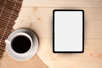 Fototapeta na wymiar Digital tablet and cup of coffee on wooden desk. Simple workspace or coffee break 