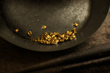 Found gold. gold panning or digging. Gold on wash pan. Intentionally shot with low key shadows and shallow depth of field.