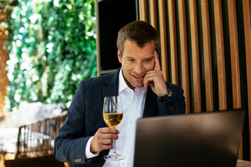 Handsome businessman dressed in the suit drinking wine. Businessman enjoying in the restaurant.