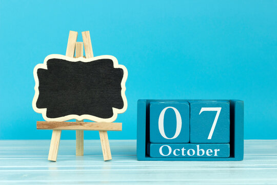 wooden calendar with the date of October 7 and an easel on a blue background, place for text, International Trigeminal Neuralgia Awareness Day; International Newspaper Day; World Day for Decent Work