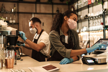 Two baristas wearing medical mask serving coffee