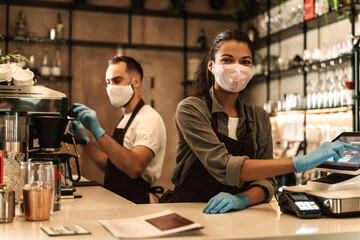 Two baristas wearing medical mask serving coffee