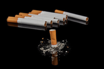 Several whole cigarettes and one smoking cigarette on a black background.