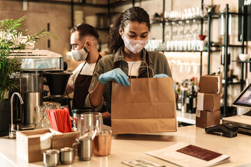 Two baristas wearing medical mask serving coffee