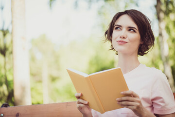 Fototapeta premium Photo of charming lovely pretty lady dreamy inspired look thinking if dragons real want ride one sitting bench read fantasy novel textbook imagining wear white shirt outdoors