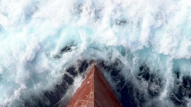 Red scratched bow of a cargo ship breaking the waves.