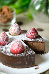 Mousse chocolate cake with strawberry and icing powder sugar. set on cafe table.