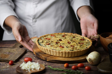 Homemade cheesy spinach quiche for brunch. set on wooden cafe table background.