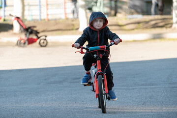 Fototapeta na wymiar Boy rides bike around the city. Child learns to ride a bicycle.
