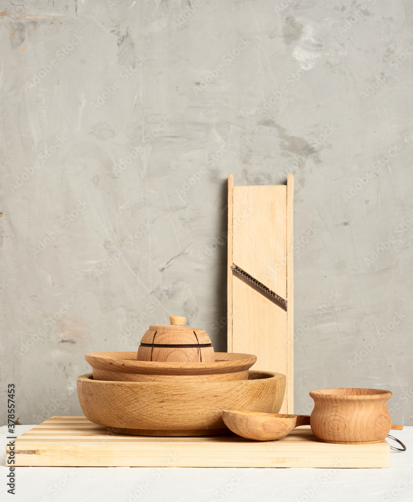 Poster stack of empty wooden round plates and new cutting board on gray background