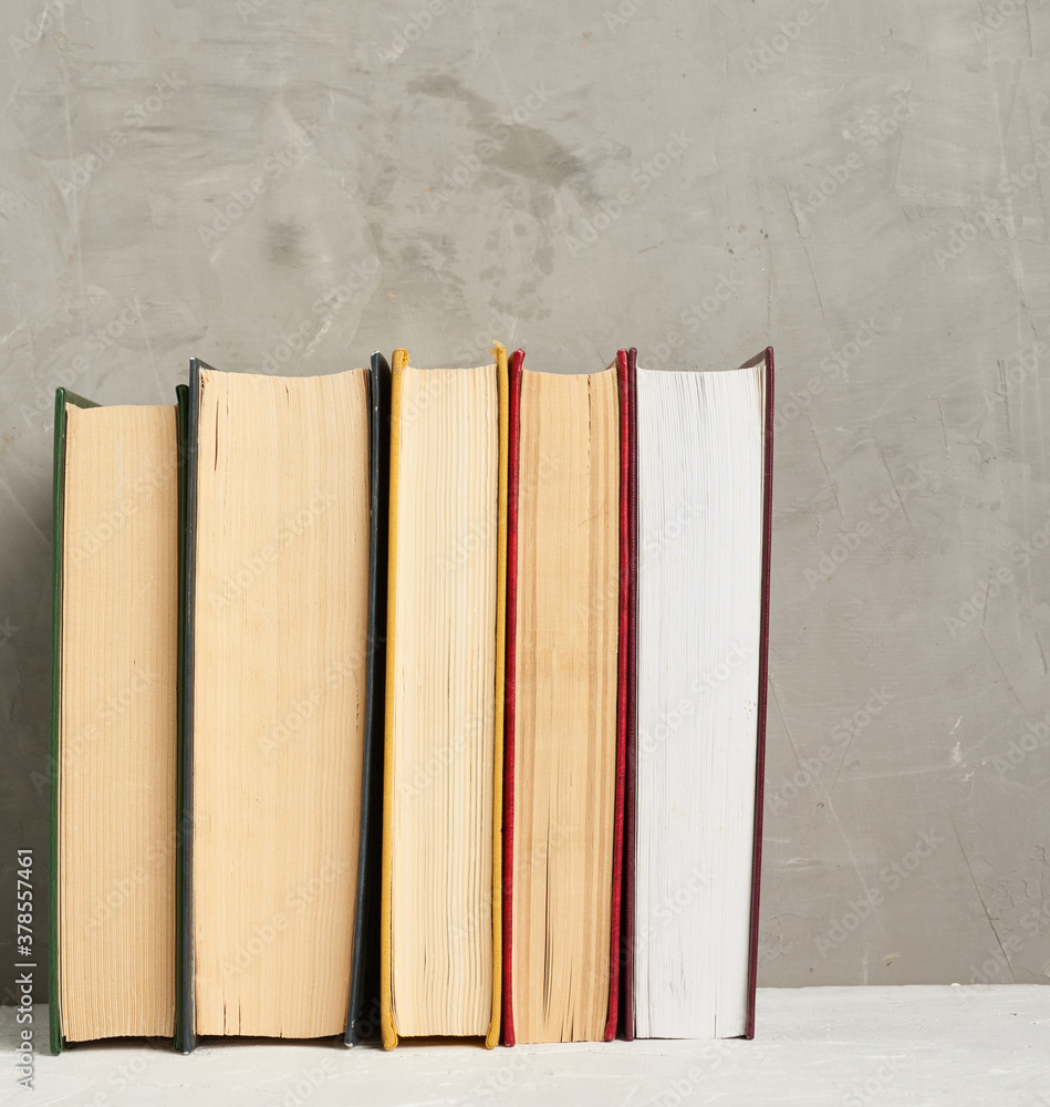 Poster stack of various hardback books on a gray background