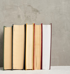 stack of various hardback books on a gray background