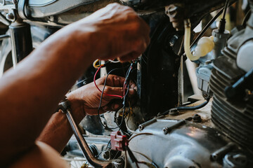 A working electrician is wiring during a motorcycle electrical installation.