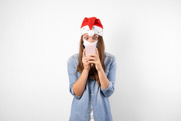 Obraz premium Young woman with phone medical mask and santa hat. Christmas shopping online on quarantine.