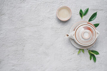 Fototapeta na wymiar Tea concept with Creamy white tea set of cups and teapot surrounded with equipment and fresh tea leaves on concrete background with copy space.