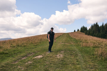 Man climbs uphill mountain. Sporty clothes and backpack. Hiking through forest in summer. A path...