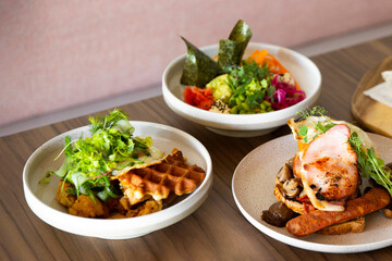 All day big breakfast poke bowl & waffles on cafe table setting under natural light.