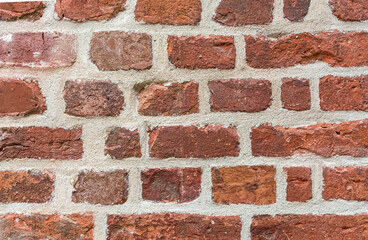 Background old masonry of red brick. Plaster, concrete, cement. Cracks, peeling, voids. Close-up