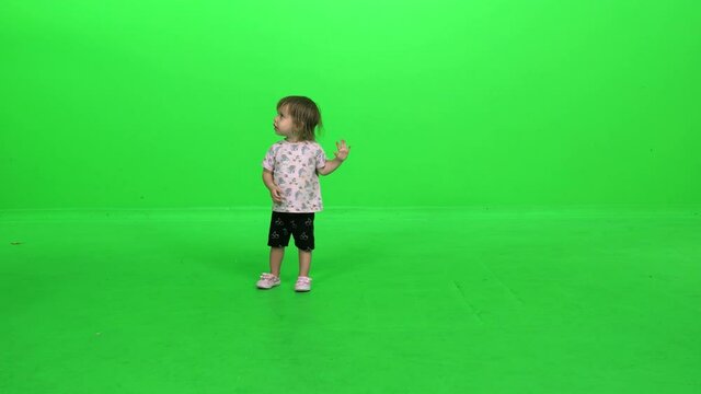 Cute little toddler dancing cheerfully over green screen.