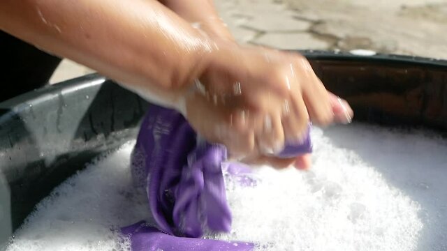 Women washing clothes by hand with detergent in enamelware. Household work and hygiene concepts. 