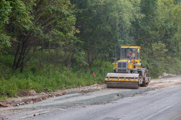 Summer, 2016 - Primorsky Krai, Russia - Repair of a bad road. Workers pave a bad road in a forest in Russia.